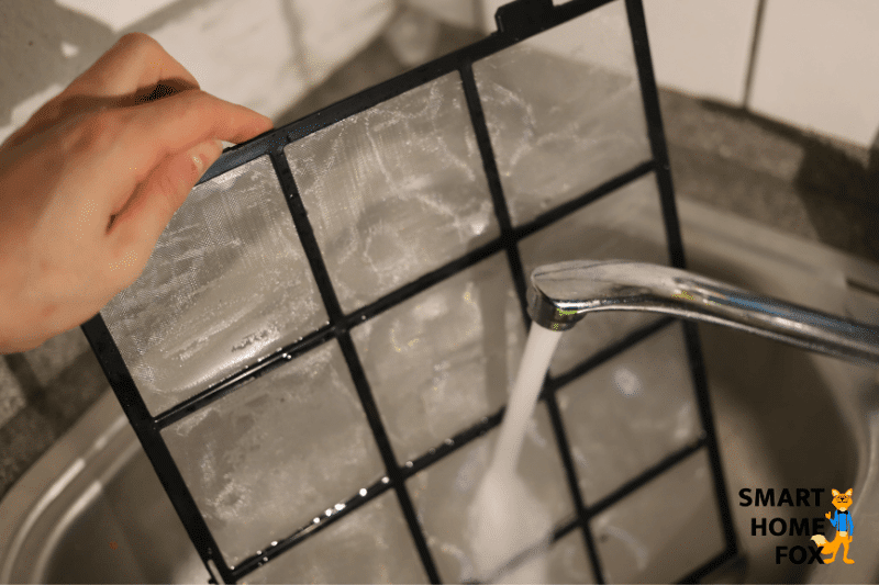 Der Vorfilter eines Luftreinigers wird unter fließendem Wasser gespült